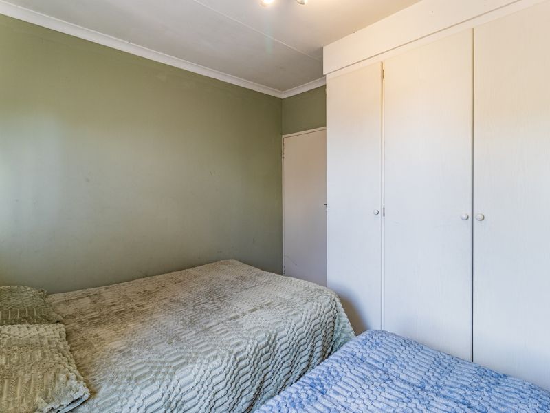 A bedroom featuring built-in cupboards and green painted walls, offering a functional space with standard finishes.