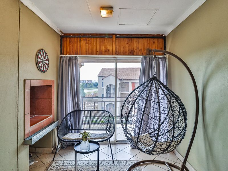 Enclosed balcony featuring a built-in braai, tiled flooring, and sliding glass doors leading to an outdoor view.
