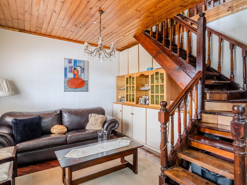 Living room featuring a timber ceiling, parquet flooring, and a prominent wooden staircase with built-in storage cabinetry.