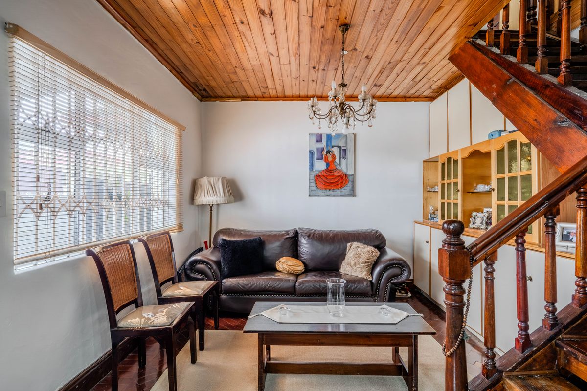 A living room featuring a timber tongue and groove ceiling, parquet flooring, and a built-in wooden staircase with integrated cabinetry.