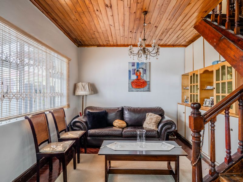 A living room featuring a timber tongue and groove ceiling, parquet flooring, and a built-in wooden staircase with integrated cabinetry.