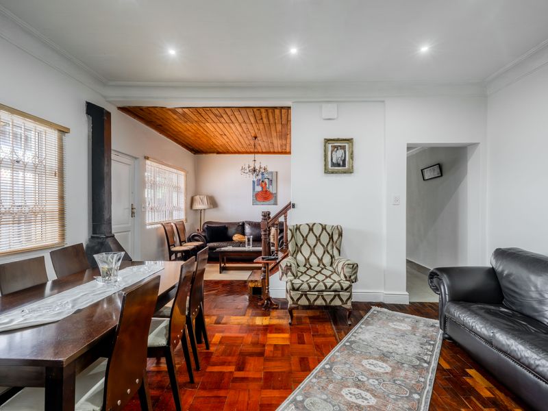 Open-plan living and dining area featuring classic parquet flooring, a wood-paneled ceiling section, and a prominent freestanding fireplace.