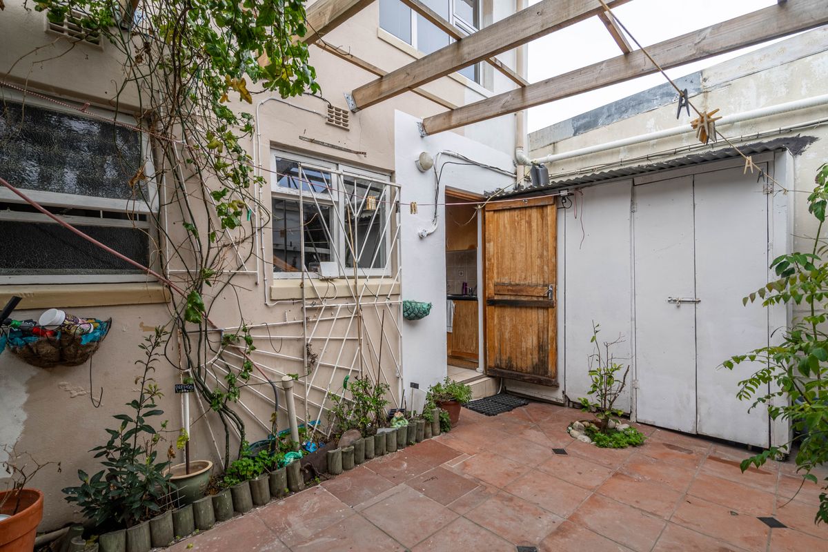 A private rear courtyard featuring terracotta tiling, a timber pergola, and direct access to the kitchen area.