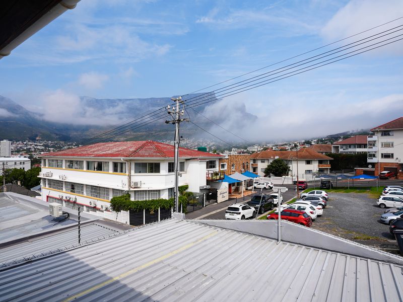 Elevated view overlooking the surrounding neighborhood and mountain range, featuring a metal roof in the foreground.