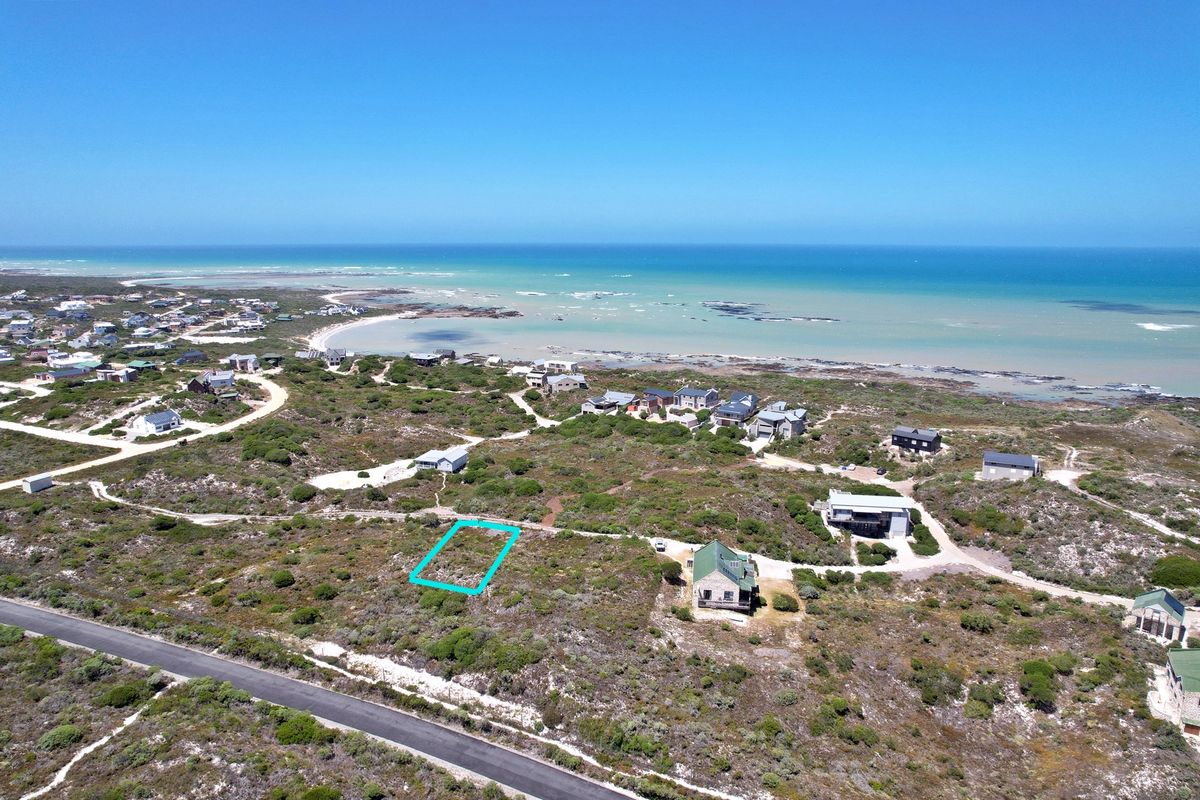 Aerial view of a vacant residential plot situated in a coastal area with surrounding natural vegetation and proximity to the ocean.