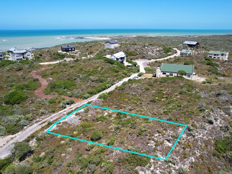 Aerial view of a vacant residential plot situated in a coastal estate, featuring natural vegetation and proximity to the ocean.