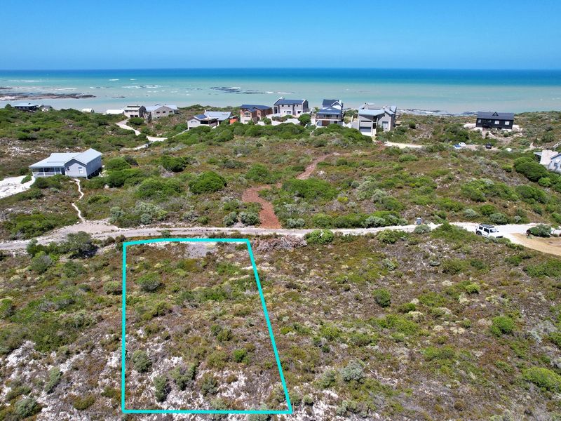 Aerial view of a vacant residential plot featuring native coastal vegetation, situated in a scenic seaside estate with ocean views.