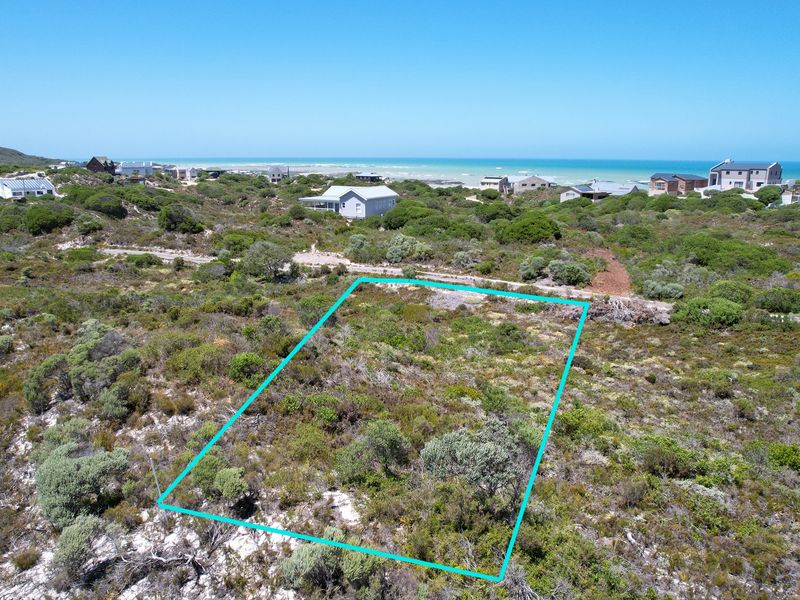 An aerial view of a vacant residential plot featuring natural coastal vegetation and proximity to the ocean.