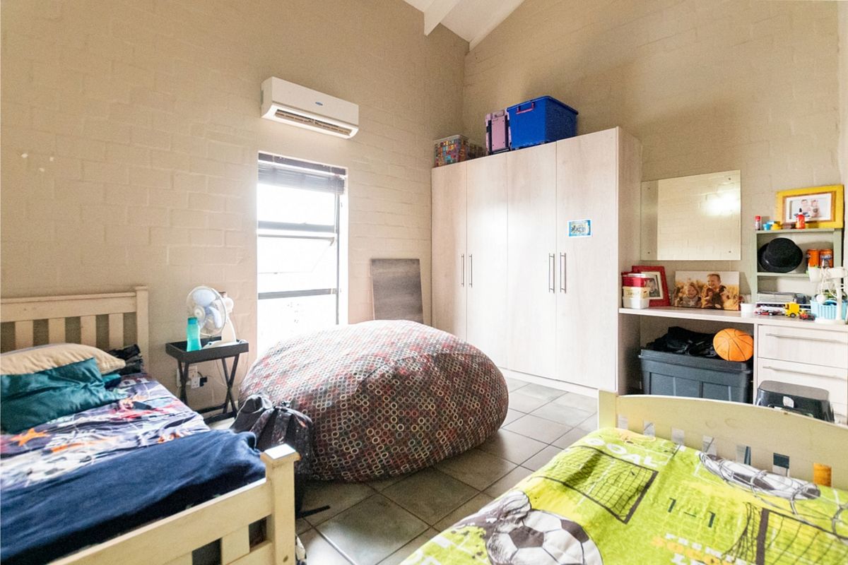A bedroom featuring tiled flooring, a vaulted ceiling, a built-in wardrobe, and a wall-mounted split-system air conditioner.