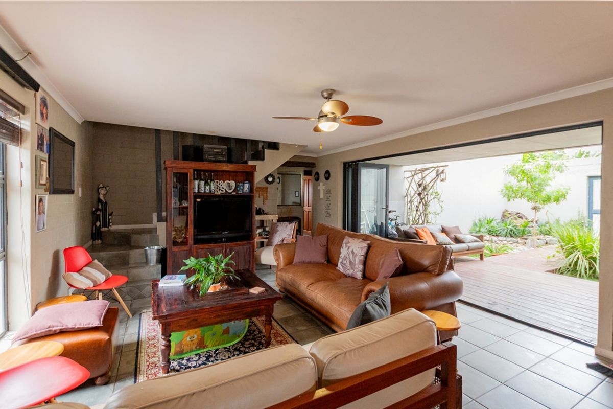 Spacious living room featuring tiled floors, a ceiling fan, and large sliding glass doors that open onto an outdoor patio area.