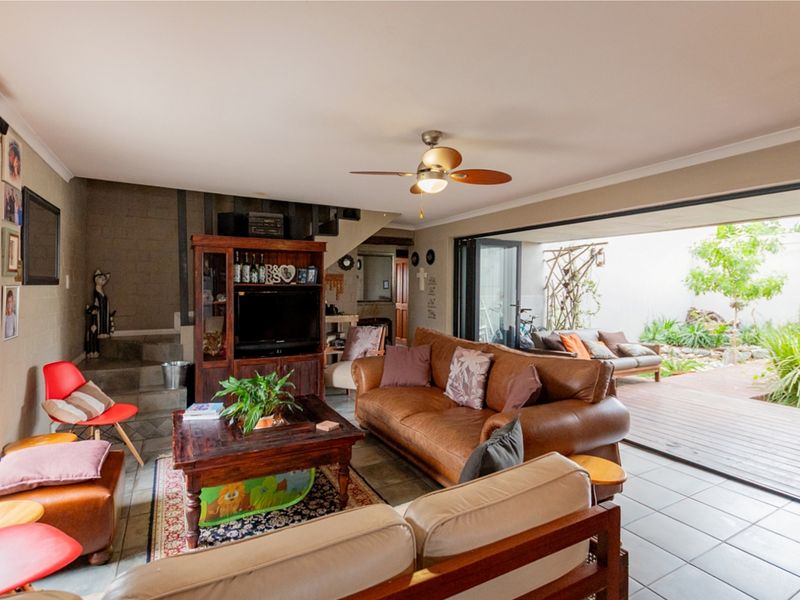 Spacious living room featuring tiled floors, a ceiling fan, and large sliding glass doors that open onto an outdoor patio area.