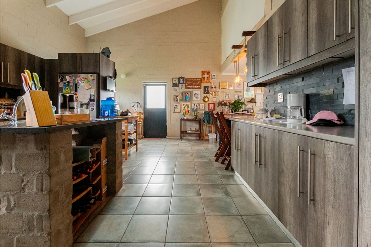 Spacious kitchen featuring vaulted ceilings, stone feature walls, extensive built-in cabinetry, and a central stone island with integrated wine storage.