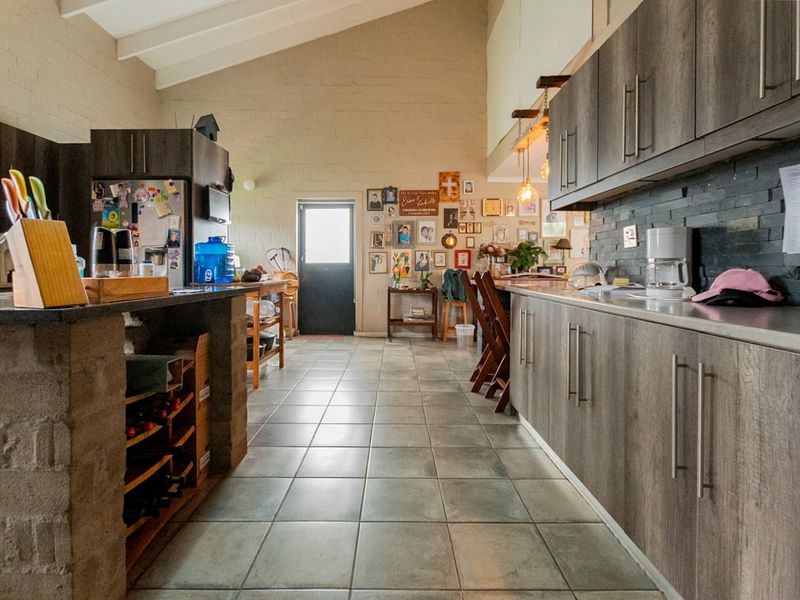 Spacious kitchen featuring vaulted ceilings, stone feature walls, extensive built-in cabinetry, and a central stone island with integrated wine storage.