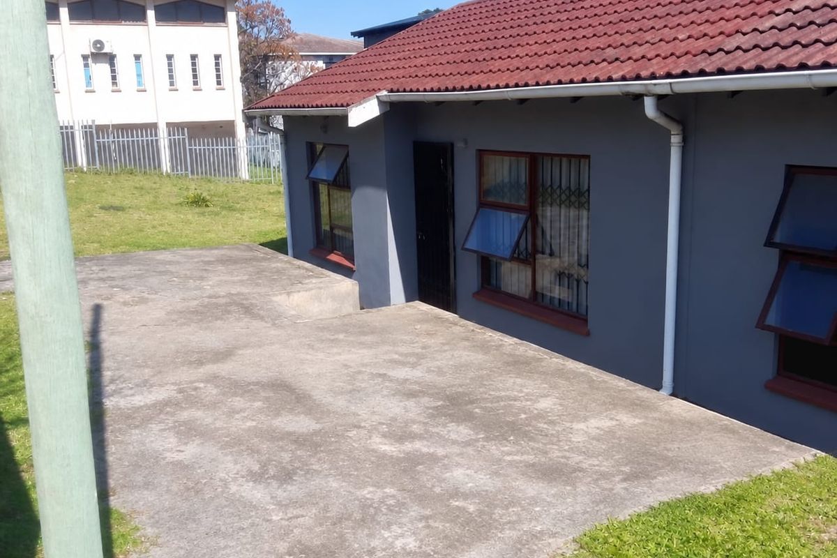 Rear view of the property featuring a concrete patio area, tiled roof, and security-fitted windows.