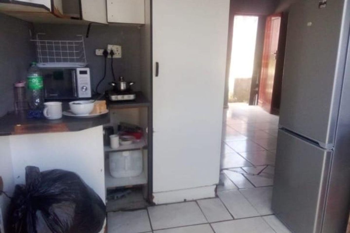 A compact kitchen area featuring tiled flooring and basic built-in cabinetry, requiring cosmetic updates to improve functionality and aesthetic appeal.