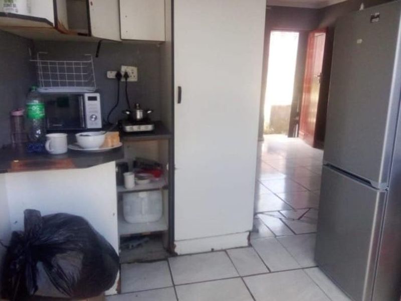 A compact kitchen area featuring tiled flooring and basic built-in cabinetry, requiring cosmetic updates to improve functionality and aesthetic appeal.