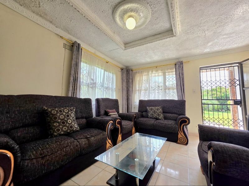 A living room featuring tiled floors, decorative ceiling detailing, and access to the exterior through a security gate.