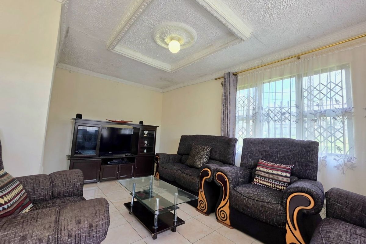 A living room featuring tiled flooring, decorative ceiling detailing, and security bars on the windows, showing signs of ceiling wear.