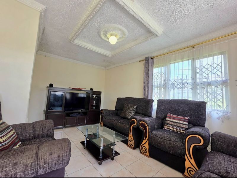 A living room featuring tiled flooring, decorative ceiling detailing, and security bars on the windows, showing signs of ceiling wear.