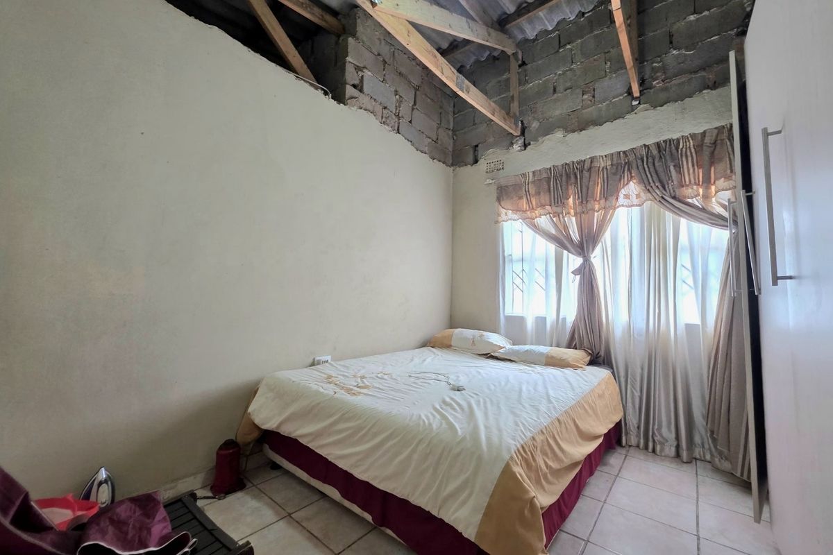 A bedroom featuring tiled flooring and a built-in wardrobe, currently requiring ceiling installation and wall finishing to complete the space.