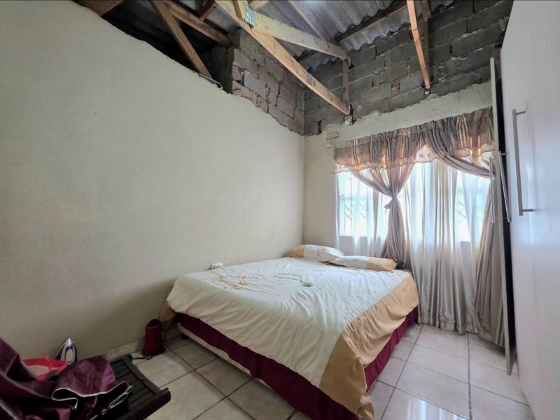 A bedroom featuring tiled flooring and a built-in wardrobe, currently requiring ceiling installation and wall finishing to complete the space.