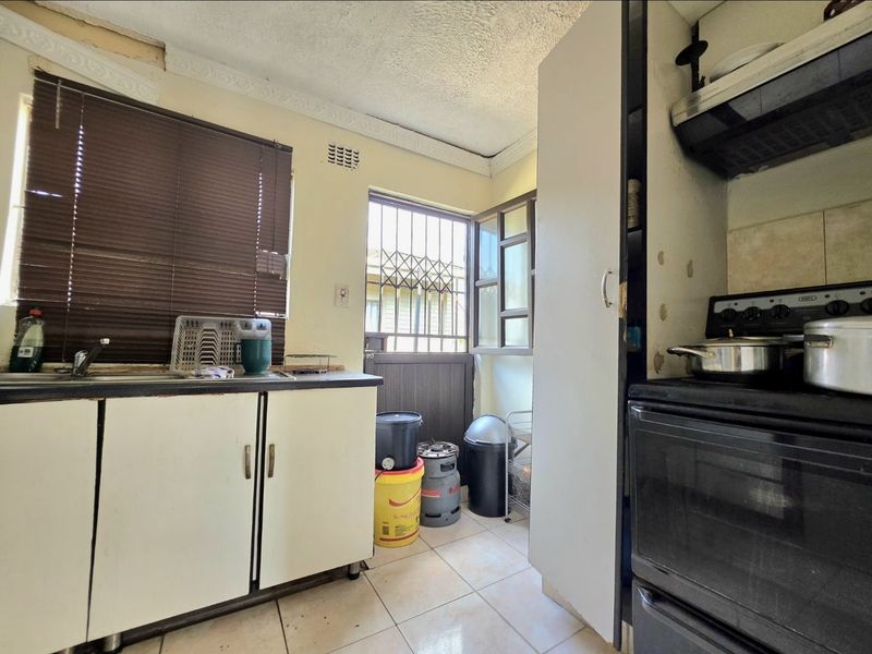 A compact kitchen featuring built-in cabinetry, a sink, and an extractor fan, requiring significant cosmetic updates and repairs to the ceiling and wall finishes.