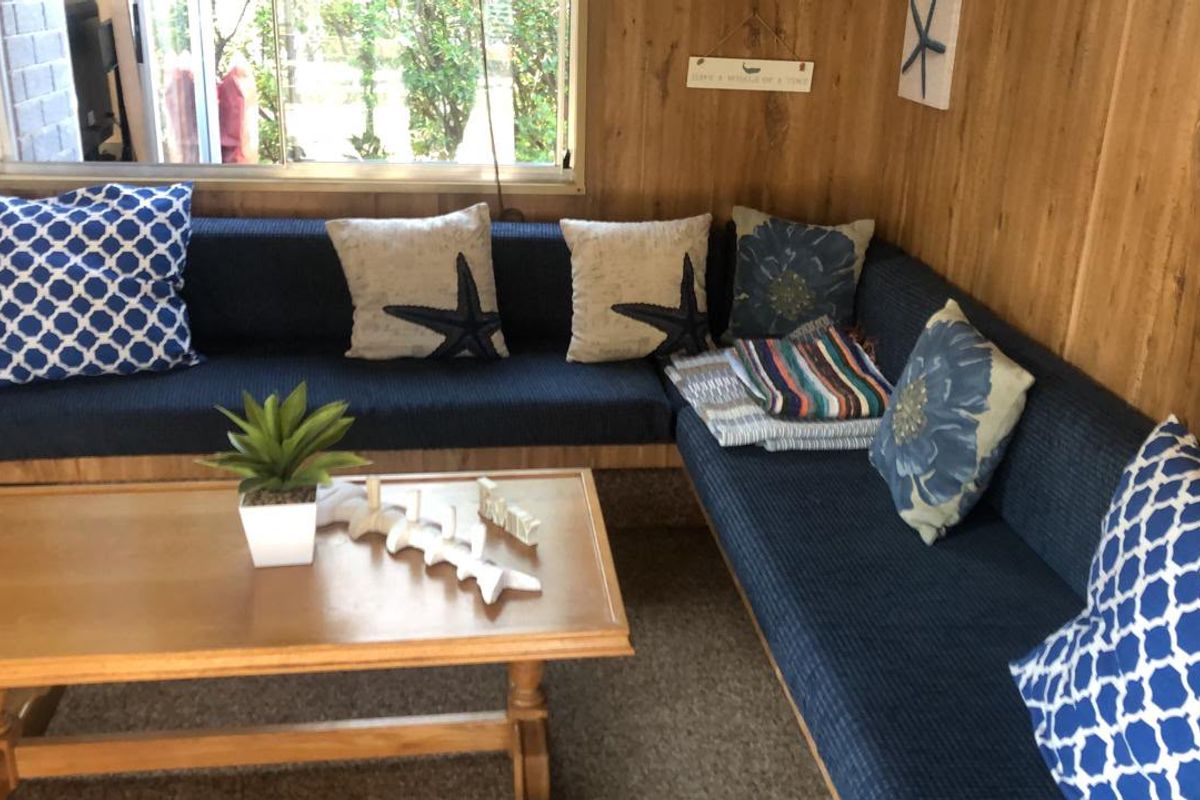 A cozy living area featuring wood-paneled walls and a large sliding window, providing a rustic and dated aesthetic.