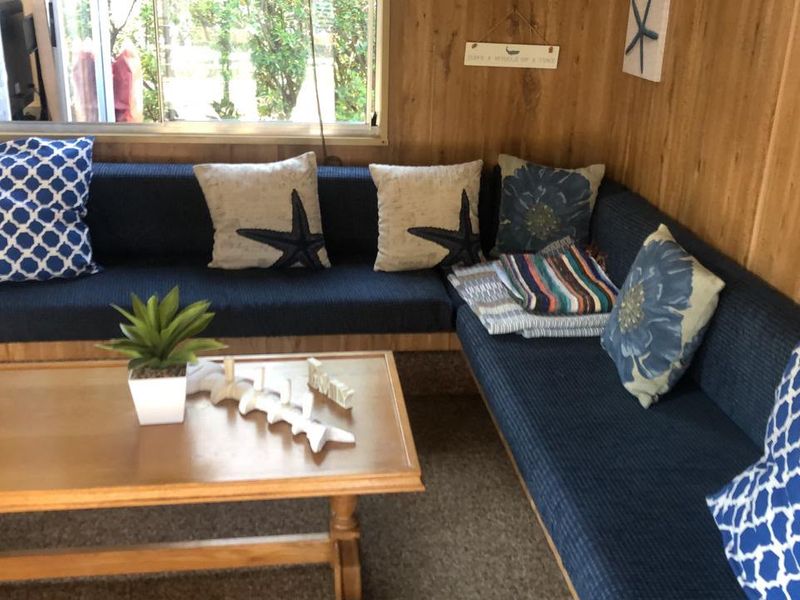 A cozy living area featuring wood-paneled walls and a large sliding window, providing a rustic and dated aesthetic.