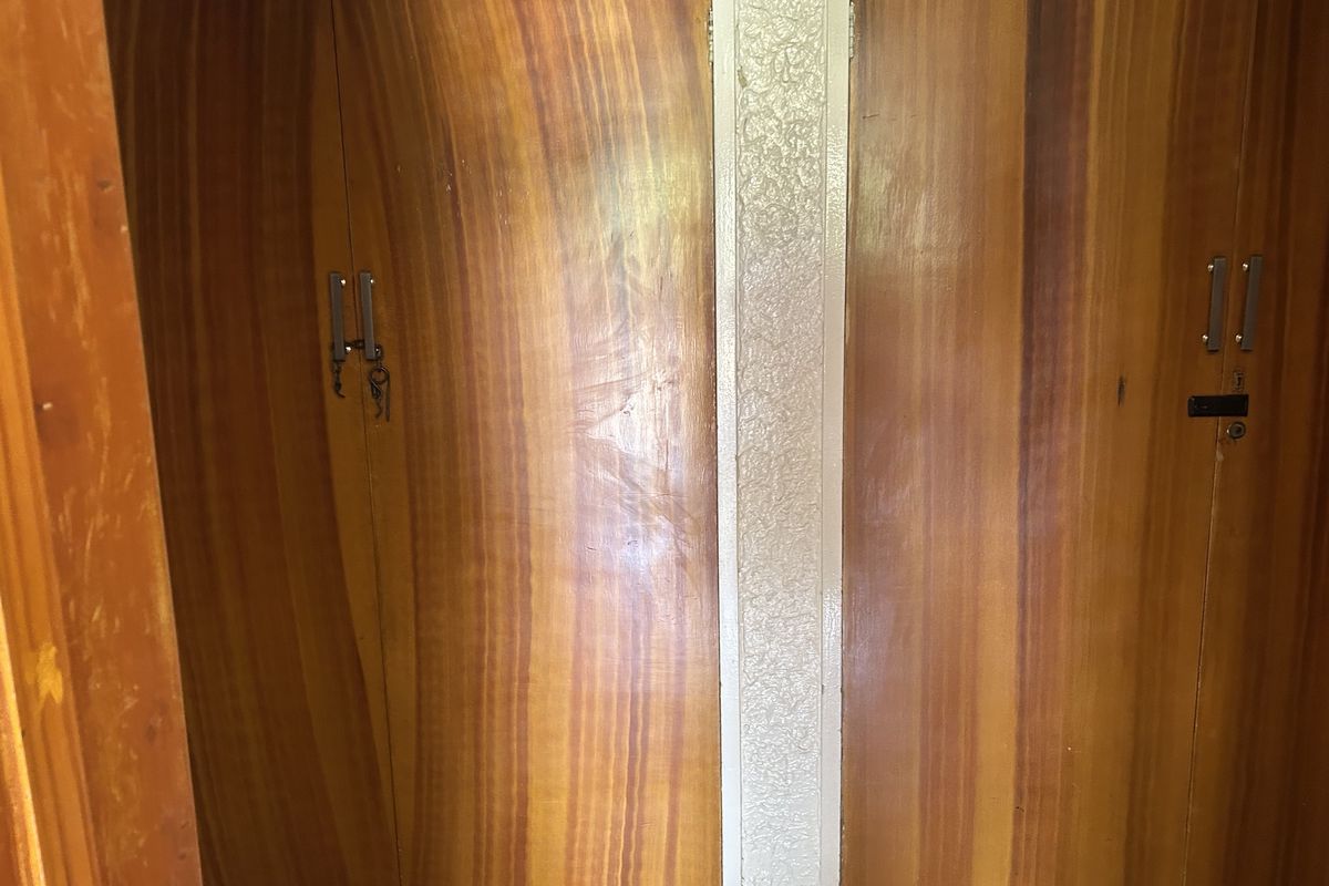 Close-up view of dated built-in wooden cupboards with visible wear and tear, suitable for renovation or modernizing.