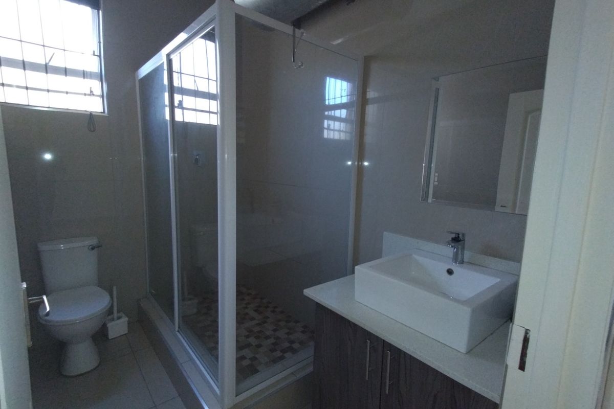 A clean, modern bathroom featuring a glass shower enclosure, a contemporary vessel sink on a vanity cabinet, and tiled finishes.