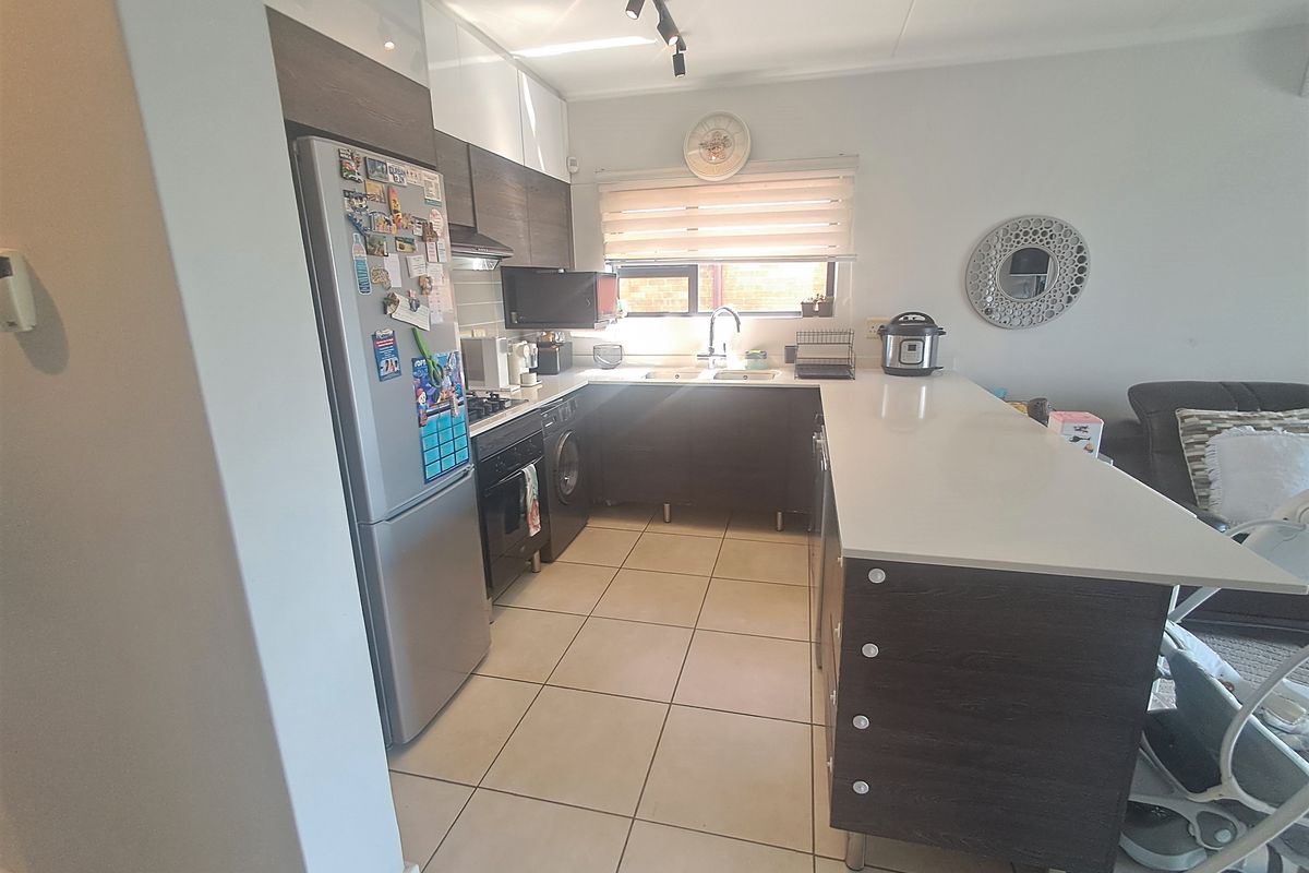Modern kitchen featuring dark wood cabinetry, stone countertops, a breakfast bar, and tiled flooring, offering a functional and contemporary cooking space.