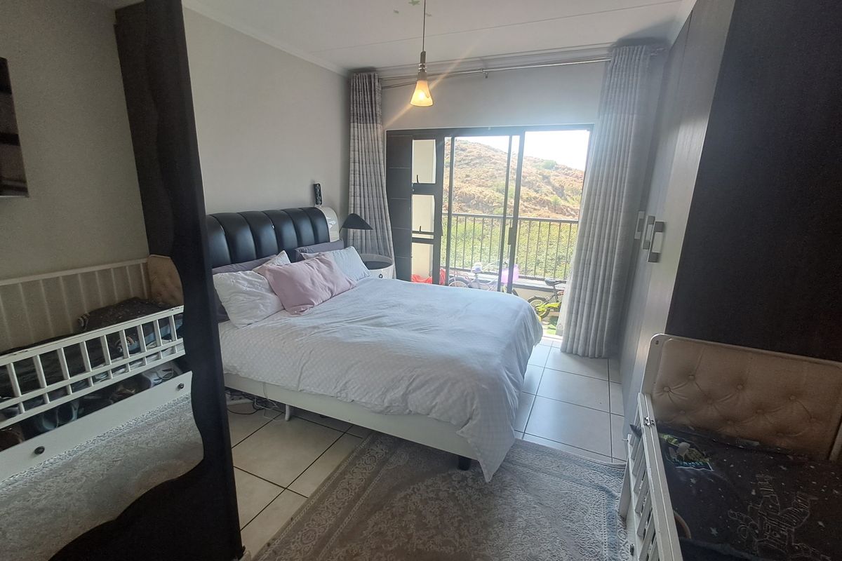 A bedroom featuring tiled flooring, built-in cupboards, and a sliding glass door that provides access to a balcony with scenic views.