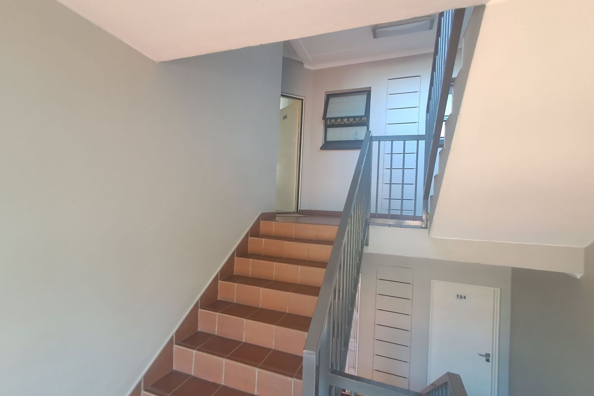 A clean and well-maintained apartment building stairwell featuring tiled steps and metal safety railings.