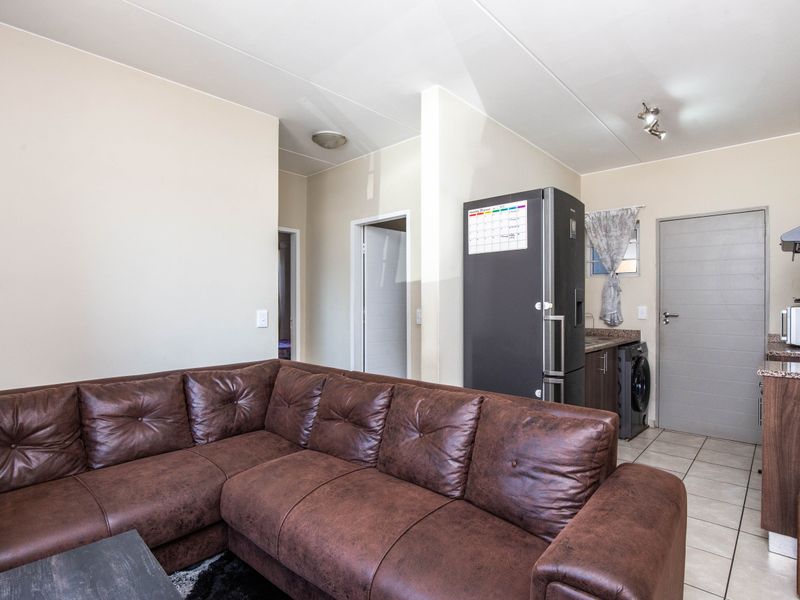 Open-plan living area featuring a compact kitchen with granite countertops, tiled flooring, and direct access to adjacent rooms.