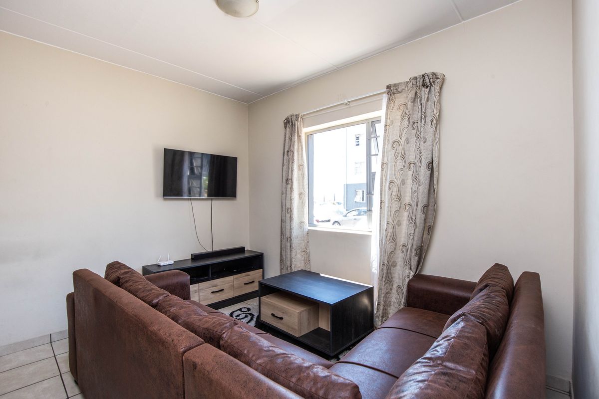A functional living room featuring tiled flooring and a window, providing a comfortable space for relaxation.