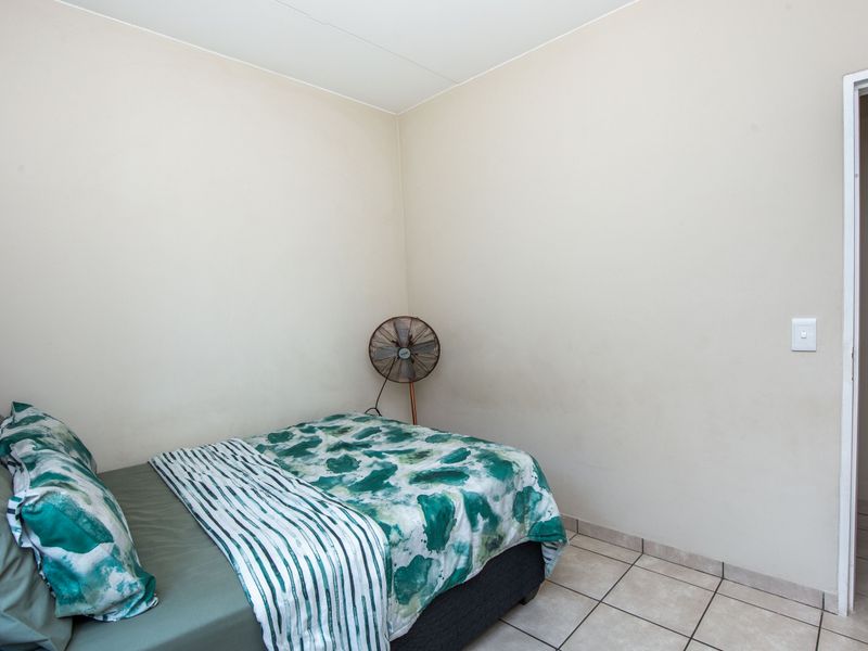 A simple bedroom featuring neutral walls and tiled flooring, providing a clean and functional space.