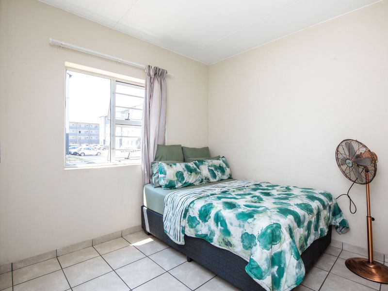 A functional bedroom featuring tiled flooring, a built-in cupboard, and a window providing natural light.
