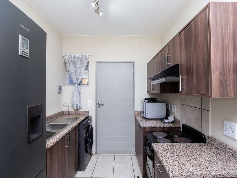 Compact kitchen featuring granite countertops, laminate cabinetry, tiled backsplash, and built-in electric stove with extractor fan.