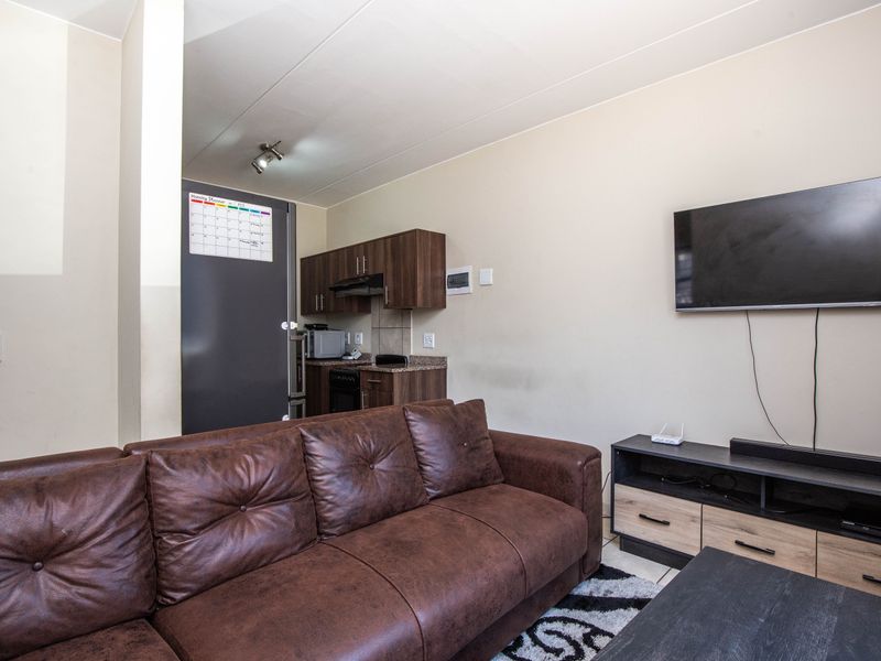 Open-plan living area featuring a compact kitchen with built-in cabinetry, granite countertops, and integrated appliances, seamlessly connected to the lounge space.