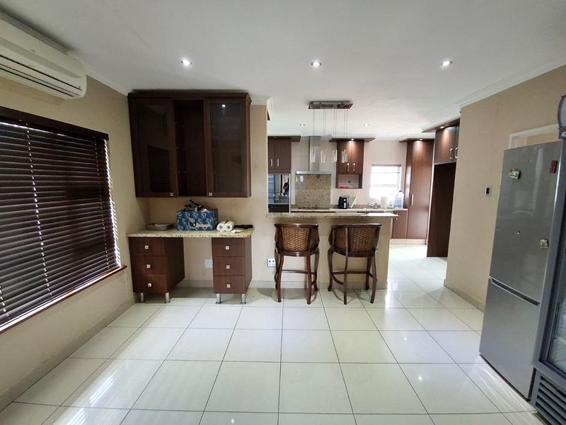 Open plan kitchen and dining area featuring granite countertops, dark wood cabinetry, a breakfast bar, and tiled flooring throughout.
