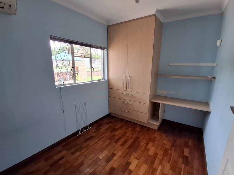 A bedroom featuring parquet flooring, a built-in wardrobe, and a built-in desk area with an air conditioning unit.
