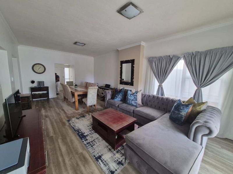 Spacious open-plan living and dining area featuring modern laminate flooring, neutral walls, and ample natural light through large windows.