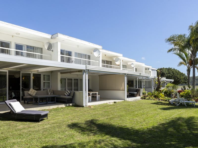 Rear view of the townhouse complex featuring covered patios, upper-level balconies, and a well-maintained communal garden area.