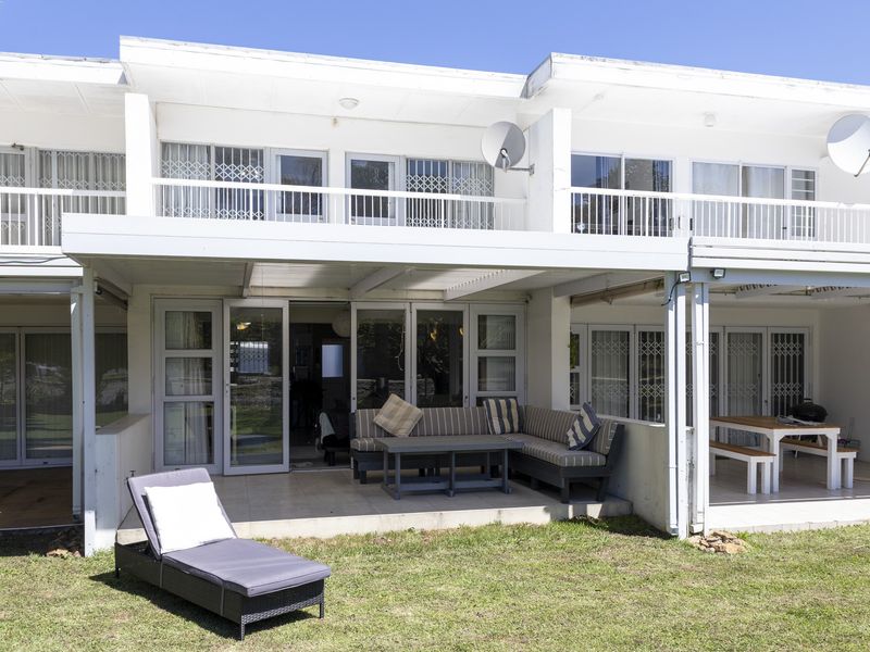 Rear view of a townhouse featuring a covered patio area, upper-level balconies, and sliding glass doors with security gates.