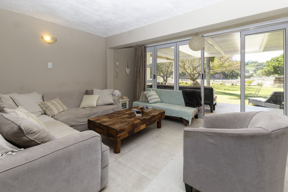 Spacious living room featuring large sliding glass doors that open onto a covered patio and garden area, providing ample natural light.