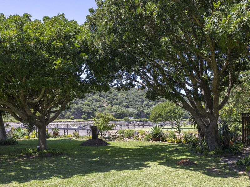 A lush, well-maintained garden featuring mature trees and a scenic view of the surrounding landscape and water.