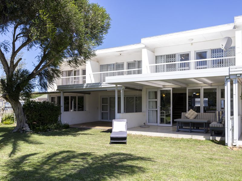 Rear view of the townhouse featuring a covered patio, upper-level balcony, and direct access to a private garden area.
