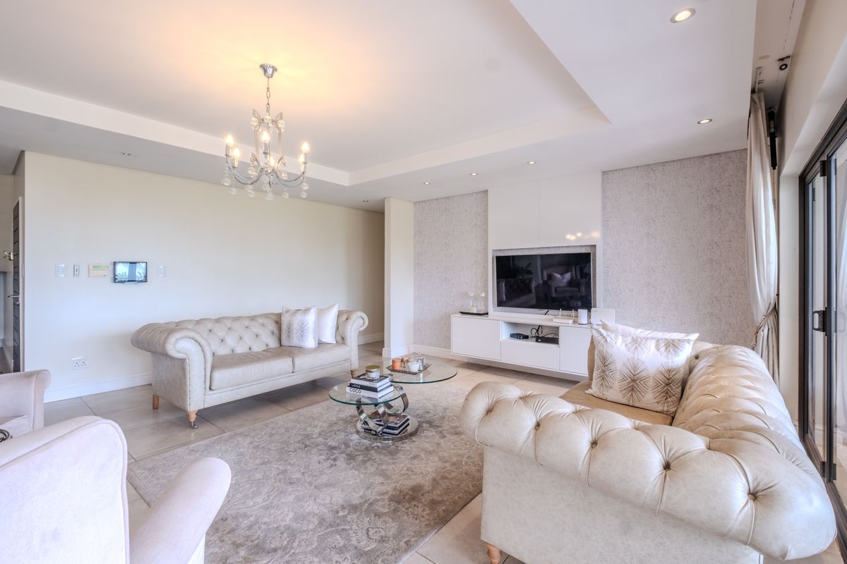 Spacious living room featuring tiled floors, recessed ceiling lighting, a crystal chandelier, and custom built-in media cabinetry with integrated storage.