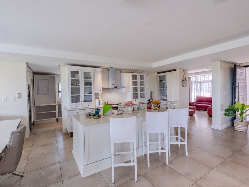 Spacious open-plan kitchen featuring a central island with stone countertops, ample built-in cabinetry, and modern finishes, seamlessly flowing into the adjacent living area.