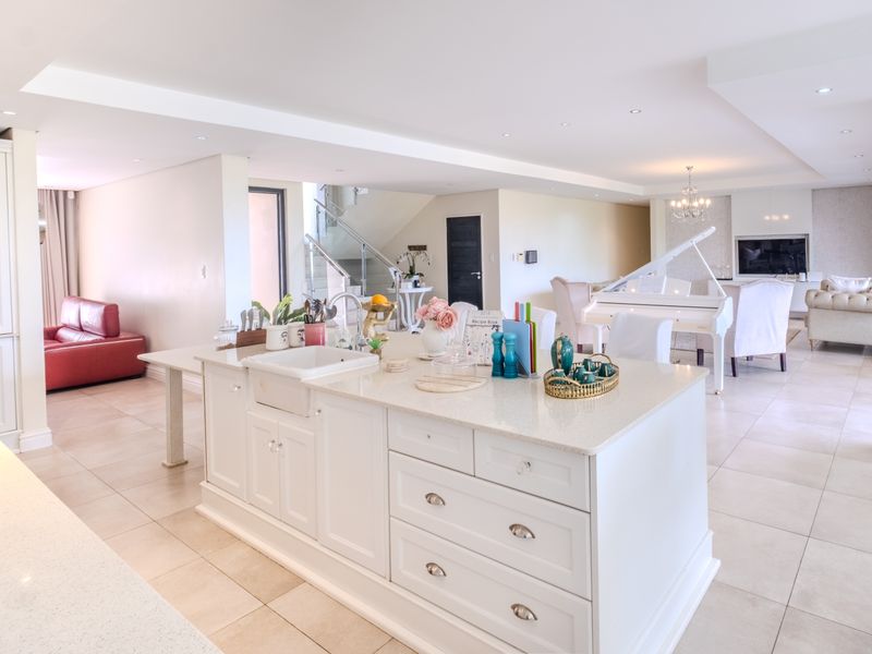 Spacious open-plan living area featuring a large kitchen island with a farmhouse sink, quartz countertops, and seamless flow into the dining and lounge spaces.